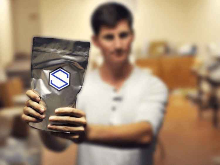 A person holding up a bag of Soylent powder